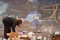 Jia Min at 6 AM.   He has been painting all night under the light of a streetlight in the middle of the road that is the subject of his painting.