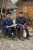 These two government accountants are checking property ownership papers in the village.  The man wearing glasses still has label in the right side of his glasses which does not matter because he has borrowed his colleague's glasses;  and notice that his colleague is missing a right eye altogether.