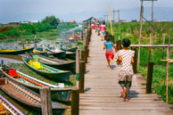 Kids running on the pier at Maing Thauk.    The market is on the land but to get to the houses one needs to go to the pier and get on a boat.   Kids learn to paddle young and they paddle standing on one leg, paddling with the other leg, so they can fish with their hands.   With this method, they paddle boats at speed like a one might drive a car, drink coffee and smoke. (35mm Kodak Ektar 100)